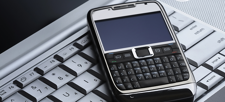 On a keyboard lies a sideways cell phone with a physical key pad, both vulnerable to a data breach