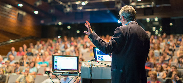 Man speaking at a conference on cybersecurity conferences