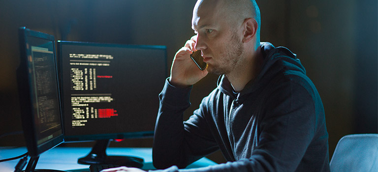 Evil man typing on computer, Insider Threats, cyber criminal.